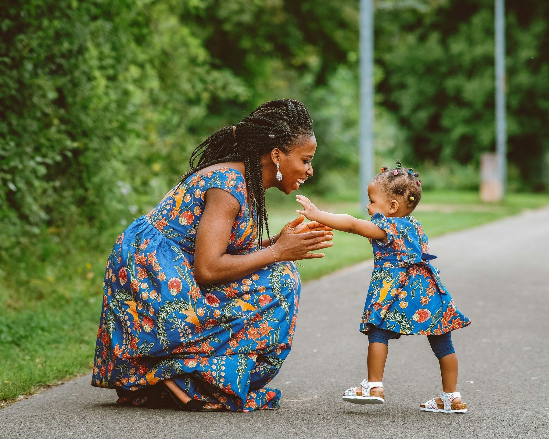 A parent and young child play together on the floor at home while a therapist coaches from beside them.